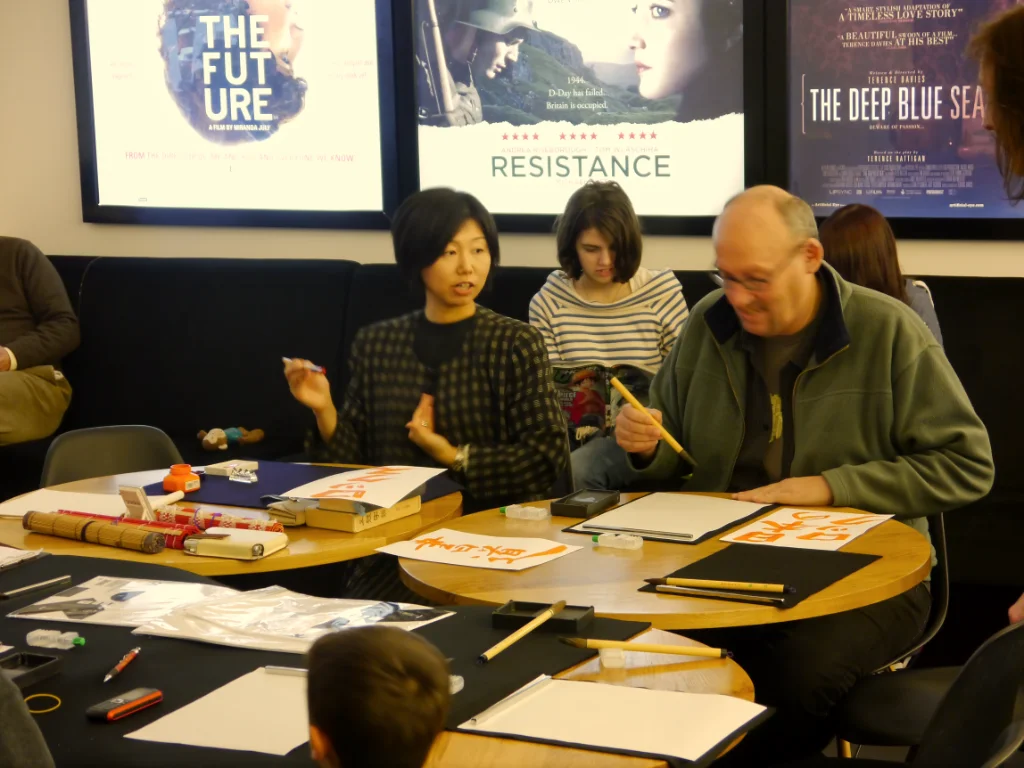 Photo of Yukiko Ayres demonstrating calligraphy at Kotatsu Festival